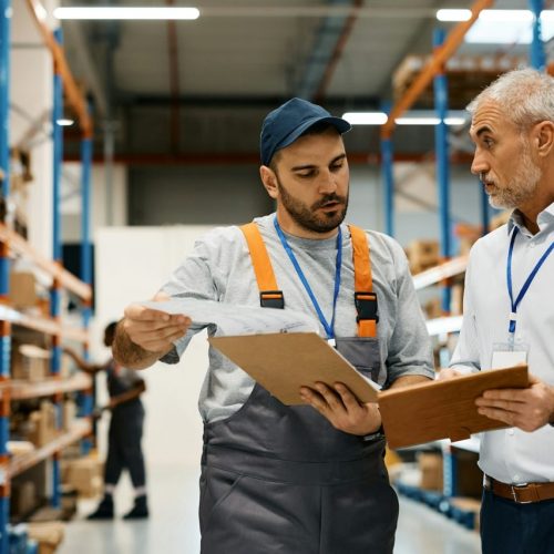 mature-warehouse-manager-and-male-worker-cooperating-while-working-at-storage-compartment-.jpg