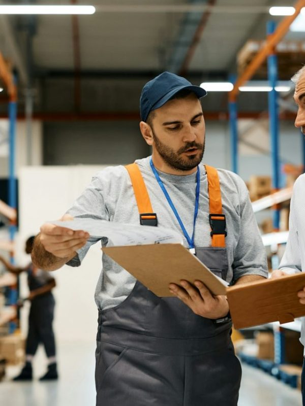mature-warehouse-manager-and-male-worker-cooperating-while-working-at-storage-compartment-.jpg